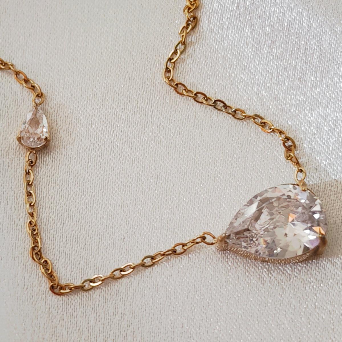 Close-up of clear teardrop-shaped stones on a gold-tone necklace.