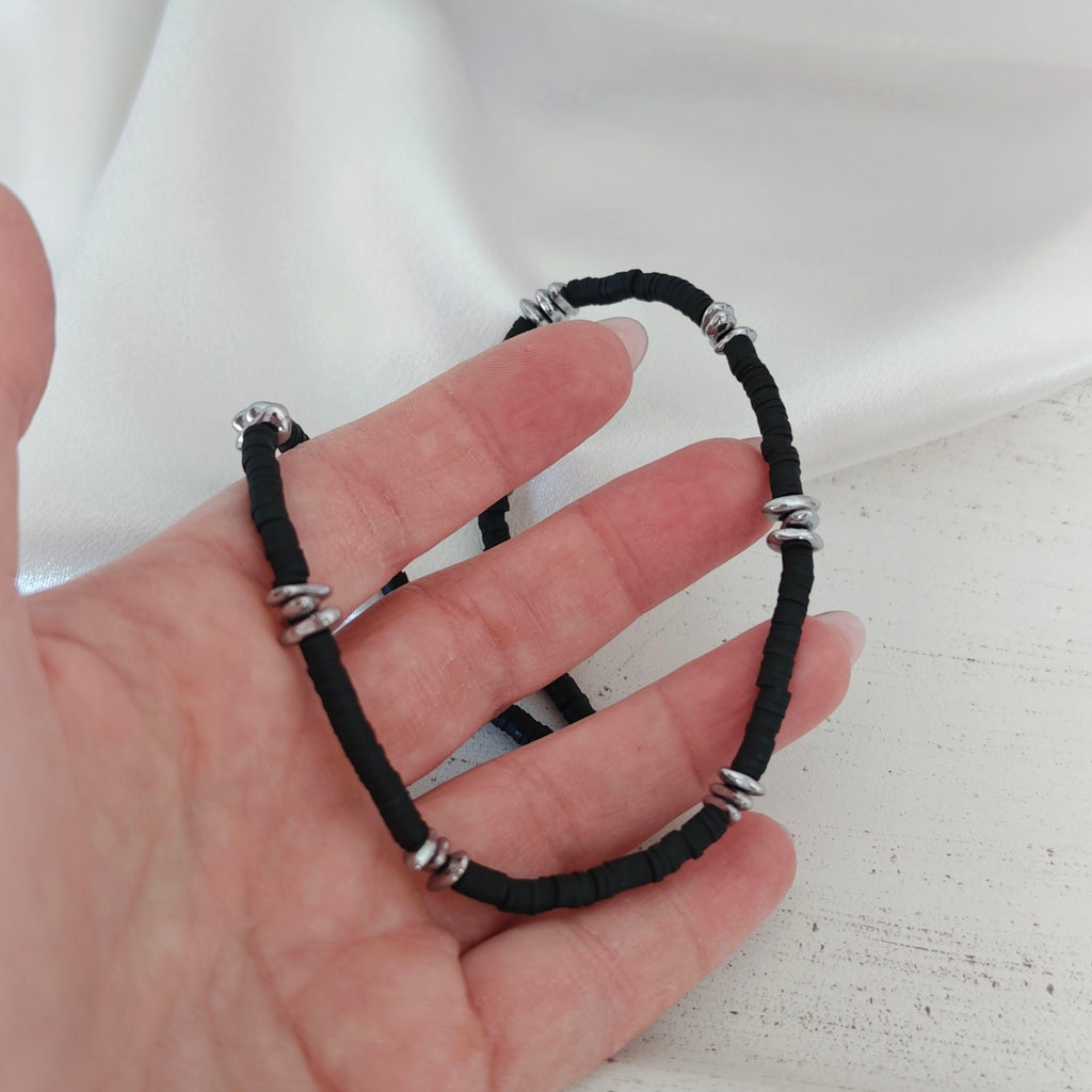 Close-up of a unisex necklace with black disc beads and silver-tone hematite pebble beads held in hand