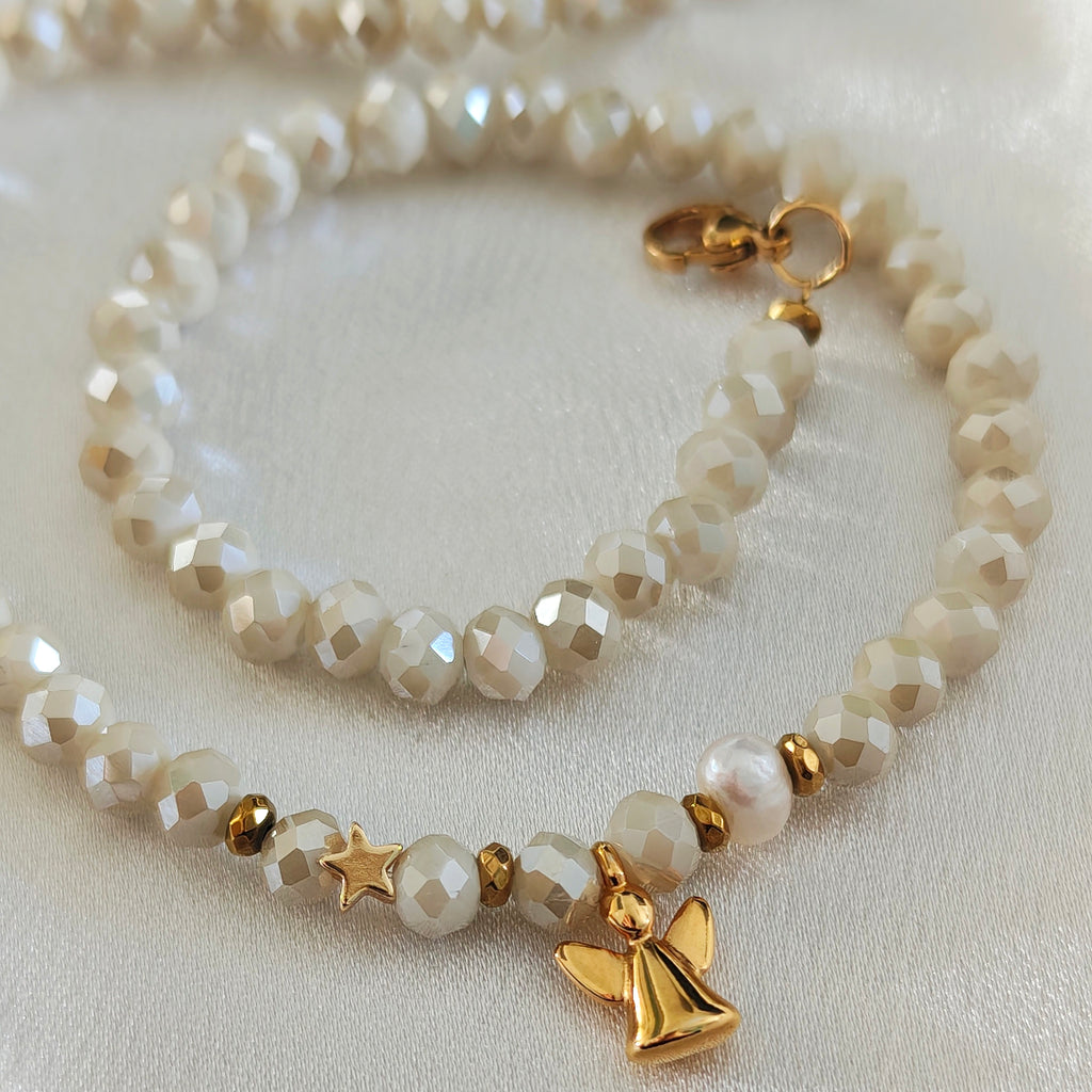 Detailed view of pearl, ivory crystals and gold-plated angel pendant.