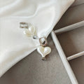 Close-up of silver hoop earrings with white pearlescent heart charms