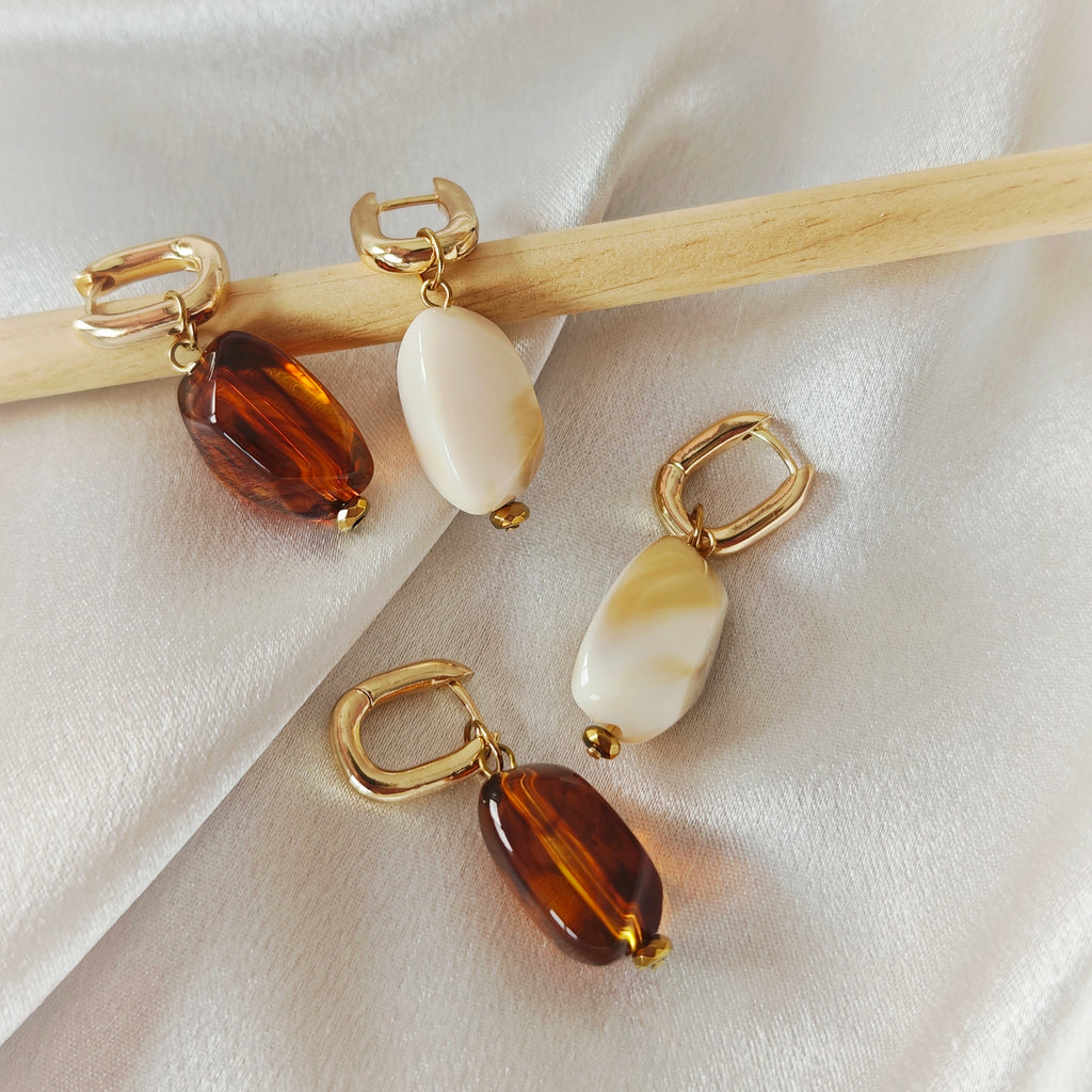Gold-tone hoop earrings with beige oval acrylic beads