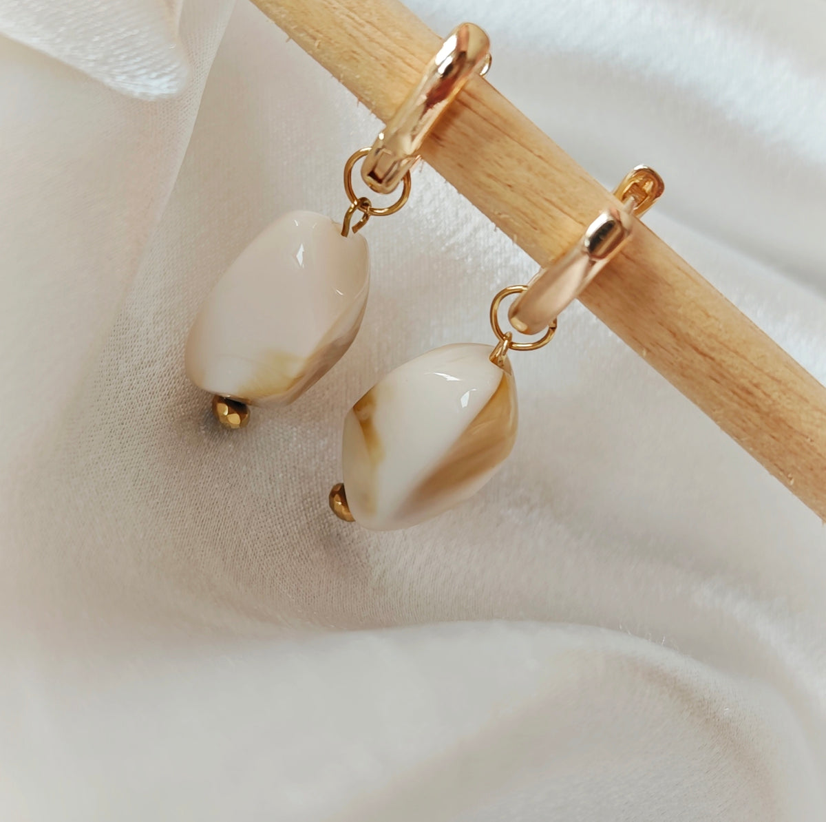 Gold-tone hoop earrings with amber-coloured oval acrylic beads