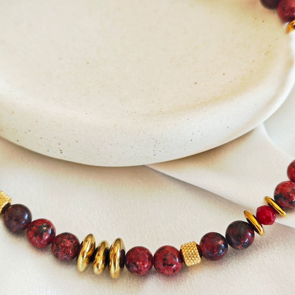 Close-up of burgundy stone beads and gold-tone hematite details on the Burgundy Rhythm necklace.