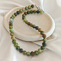 Olive Agate necklace with round olive green and brown agate beads on an ivory display.