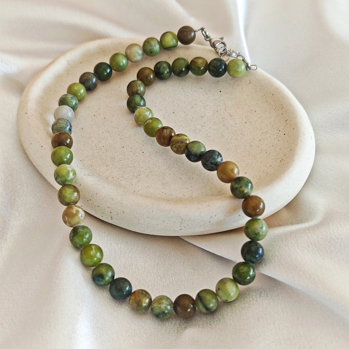 Olive Agate necklace with round olive green and brown agate beads on an ivory display.