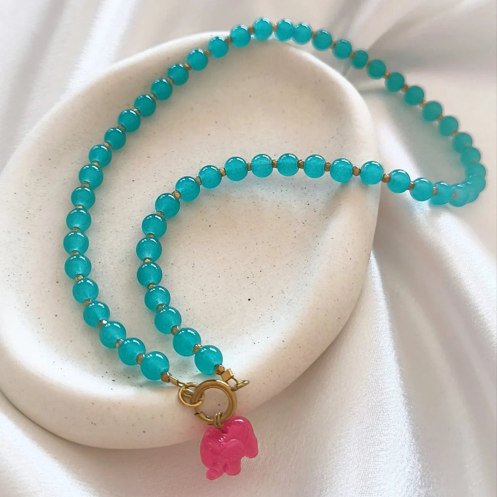 christisaccessories beaded necklace with turquoise beads, gold spacers, and a whimsical pink elephant charm.