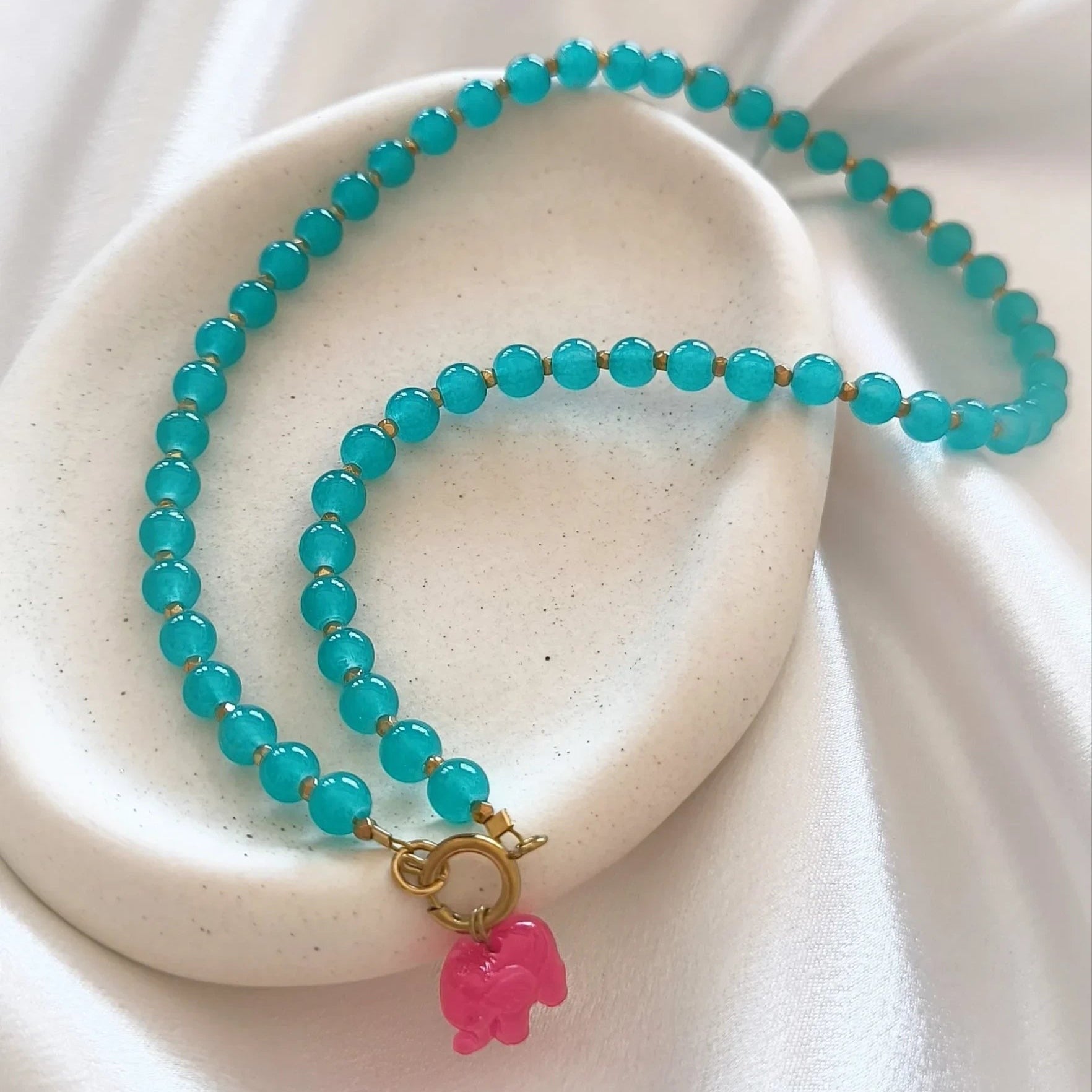 christisaccessories beaded necklace with turquoise beads, gold spacers, and a whimsical pink elephant charm.