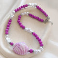 christisaccessories beaded statement necklace with a pink seashell pendant, magenta beads, and white pearls.