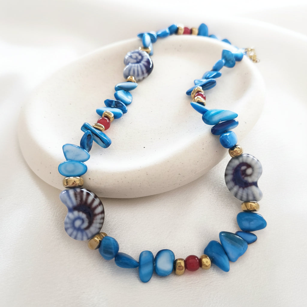 christisaccessories beaded shell necklace with blue chips, spiral shell focal beads, and gold-tone accents.