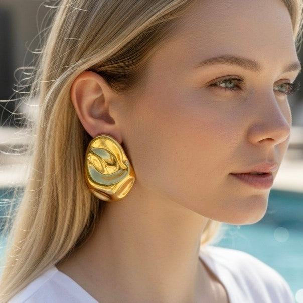 Bold oval earrings in gold and silver on white satin