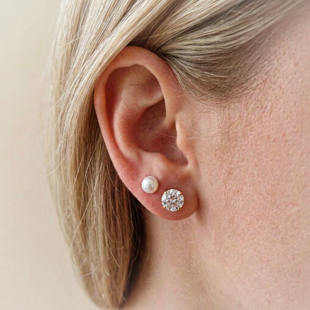 Gold pearl and clear crystal stud earrings on beige velvet display
