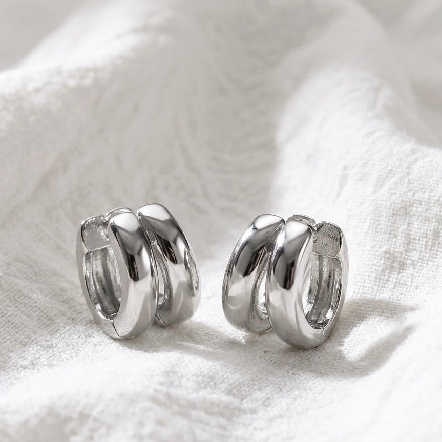 Silver double huggie hoop earrings on white linen