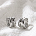 Silver double huggie hoop earrings on white linen