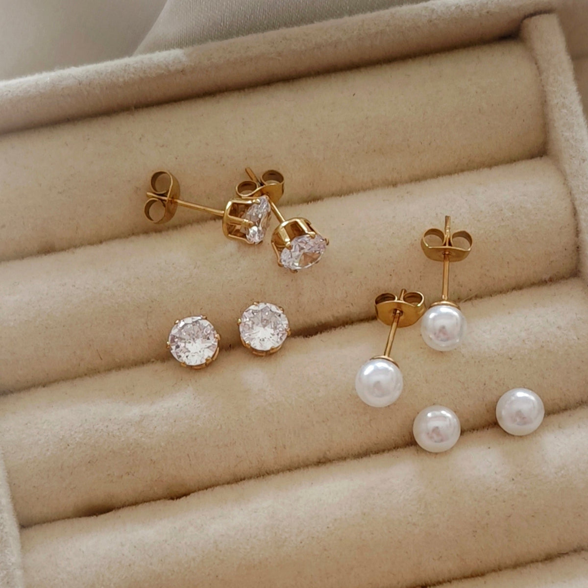 Gold stud earrings with white pearl and clear crystal worn on ear
