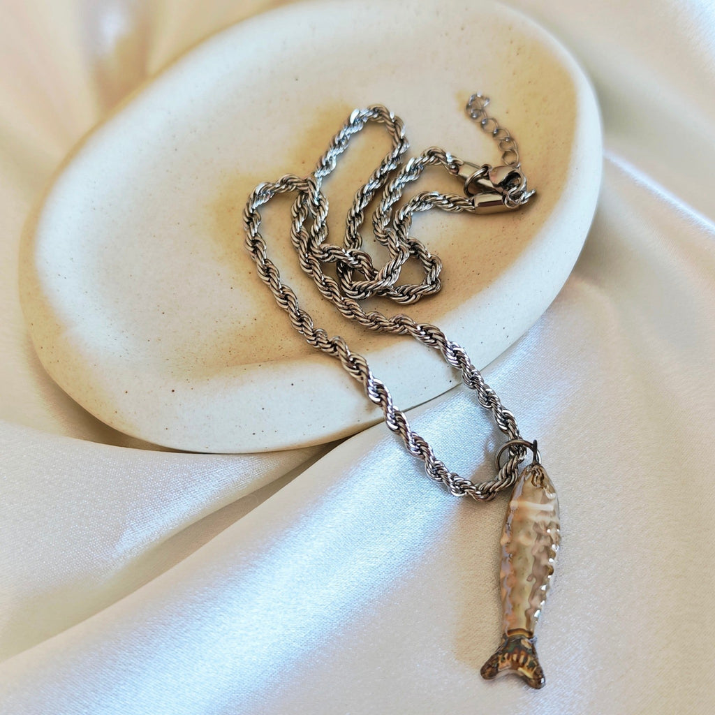 Fish pendant stainless steel rope necklace on ceramic dish