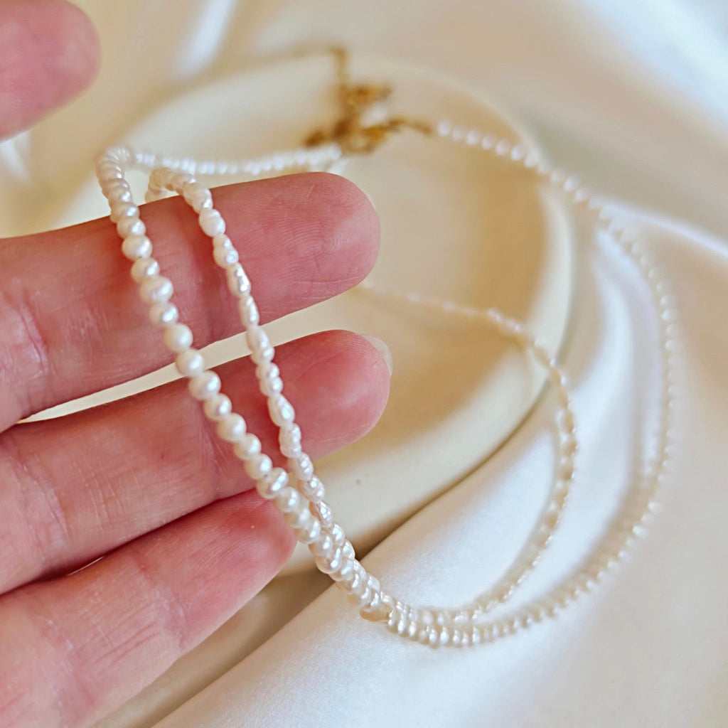Detail of tiny freshwater pearl necklace showing miniature rice and round pearls with gold clasp