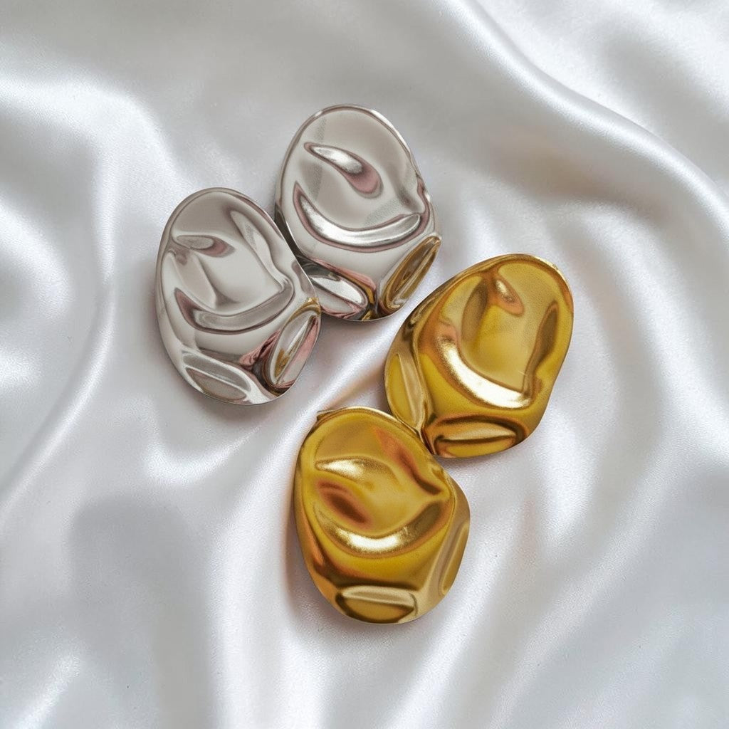 Bold oval earrings in gold and silver on white satin
