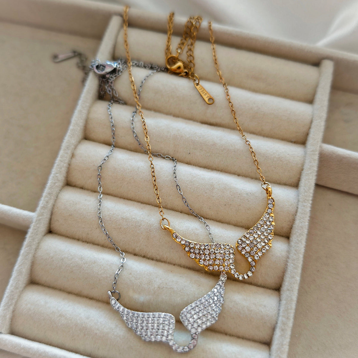 Gold and silver wings necklaces with clasps on jewelry tray