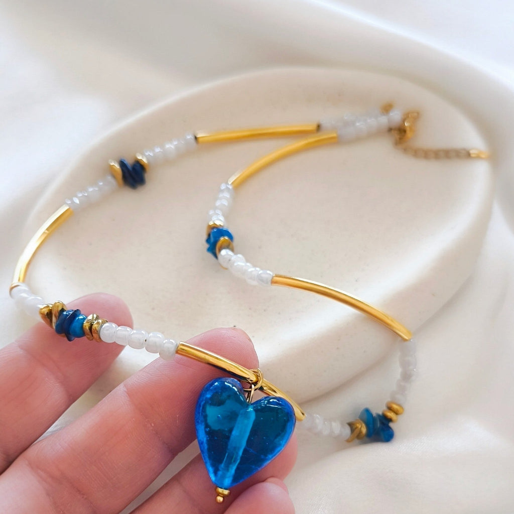 Blue heart necklace held in hand showing pendant detail