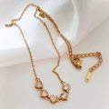 Gold-tone necklace with five sparkling heart-shaped stones on a fine chain