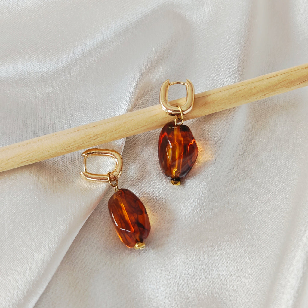 Gold-tone hoop earrings with oval acrylic beads in amber and beige